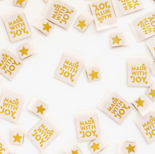 Load image into Gallery viewer, Woven center fold labels by Sarah Hearts white with gold Made with Joy and small stars and a separate small gold star label on white for stockings holiday Christmas sewing projects quilts reusable gift bags tree skirt