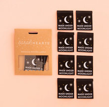 Load image into Gallery viewer, Woven center fold label by Sarah Hearts black background with fingernail moon and 2 eight point stars in white and gold dots Made Under Moonlight in white type print for garments clothing makers tote bags quilts
