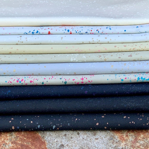 Curated fat quarter bundle of Speckled by Ruby Star Society for Moda Fabrics in shades of black gray cream white spatters of color and gold metallic are splashed across each fabric 