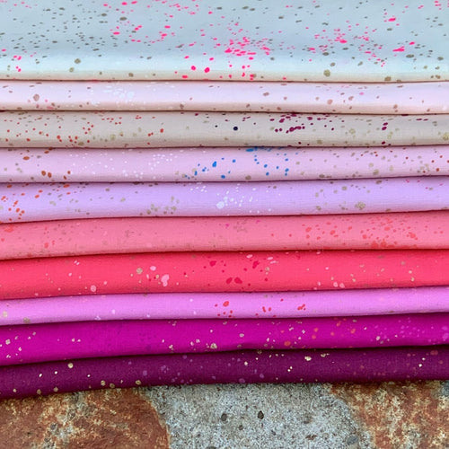Curated fat quarter bundle of Speckled by Ruby Star Society for Moda Fabrics in shades of pink ranging from deep berry to peachy pink to blush to neon spatters of color and gold metallic are splashed across each fabric 