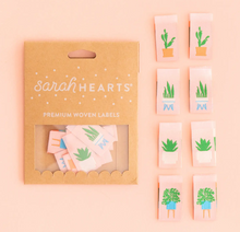 Load image into Gallery viewer, Woven labels by Sarah Hearts with bright green succulents and houseplants in modern blue white and terra cotta containers centerfold double sided design soft and machine washable for use in garments quilts clothing purses bags and sewing projects 
