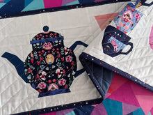 Load image into Gallery viewer, Quiet Play Tea Party Table Runner Down the Rabbit Hole fabric by Jill Howarth Teapot teacups and stacks of cups with Alice in Wonderland scenes in navy pink and peach on a solid white background includes pattern backing binding cotton quilt fabric
